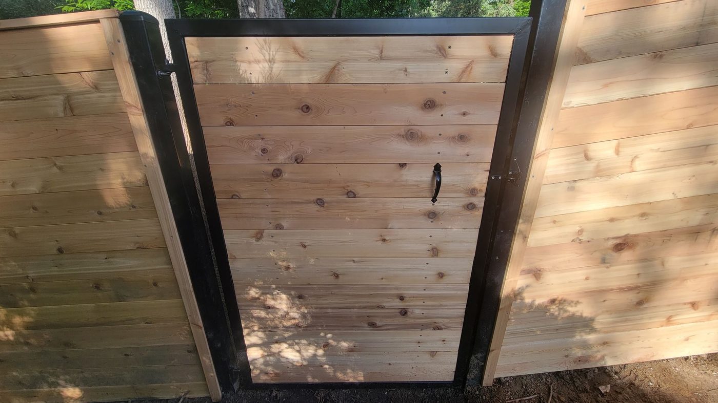 Modern horizontal cedar fence with a black steel-framed gate